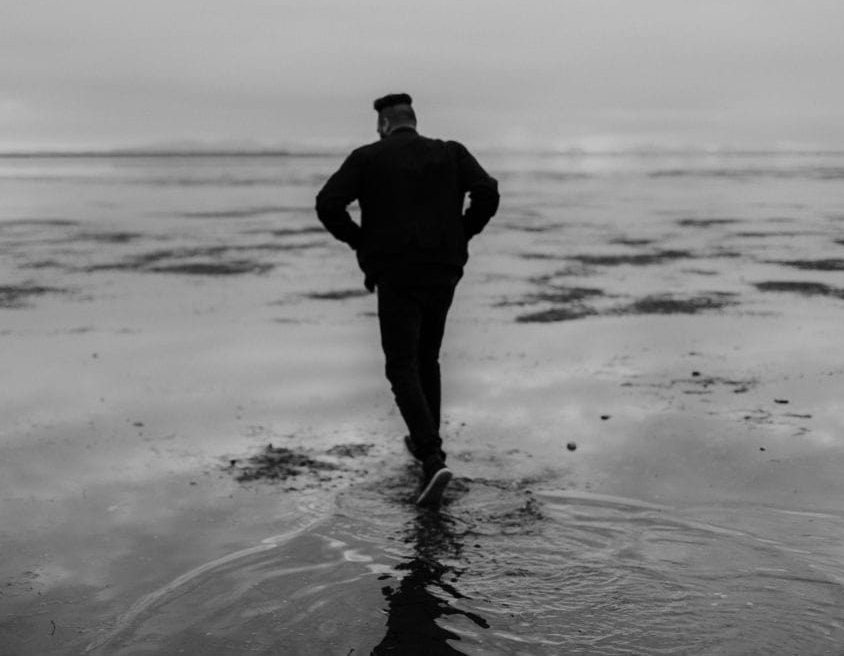 Man with depression walking on beach